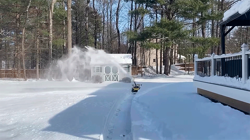 Робот-снегоуборщик Yarbo Snow Blower выбрасывает снег на большую дистанцию при очистке заснеженного двора зимой.